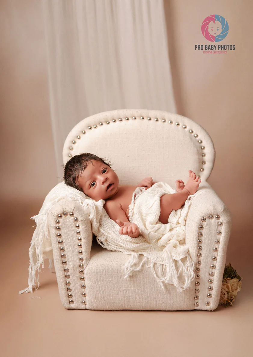 Newborn baby photographed with a small chair prop